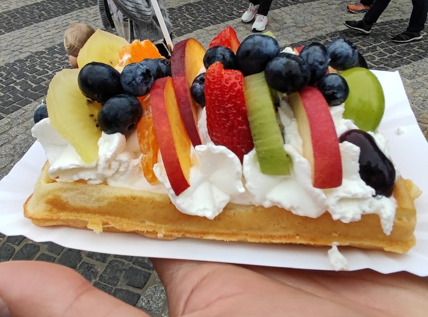 A waffle with whipped cream and fruits.