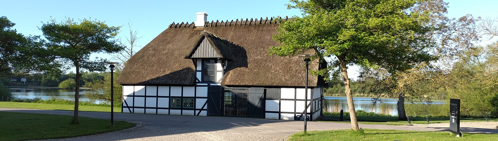 A picture taken at the Sandbjerg Gods retreat in 2024, showing a timber house with straw-covered roof